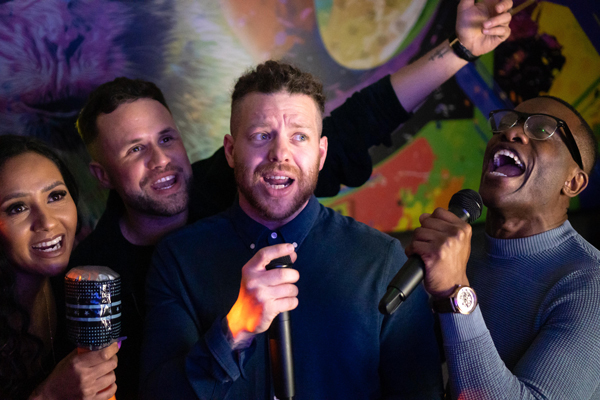 A group  of 3 men and 1 woman singing in karaoke room